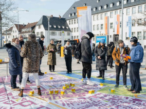 Eine kleinere Menschenmenge steht auf einer Bodenkarte der Rüsselsheimer Innenstadt